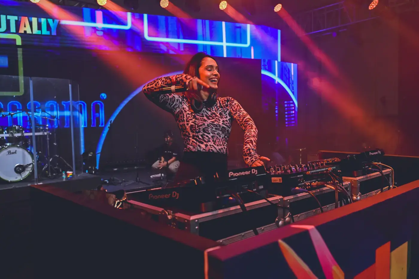 A DJ performing behind the decks under stage lighting